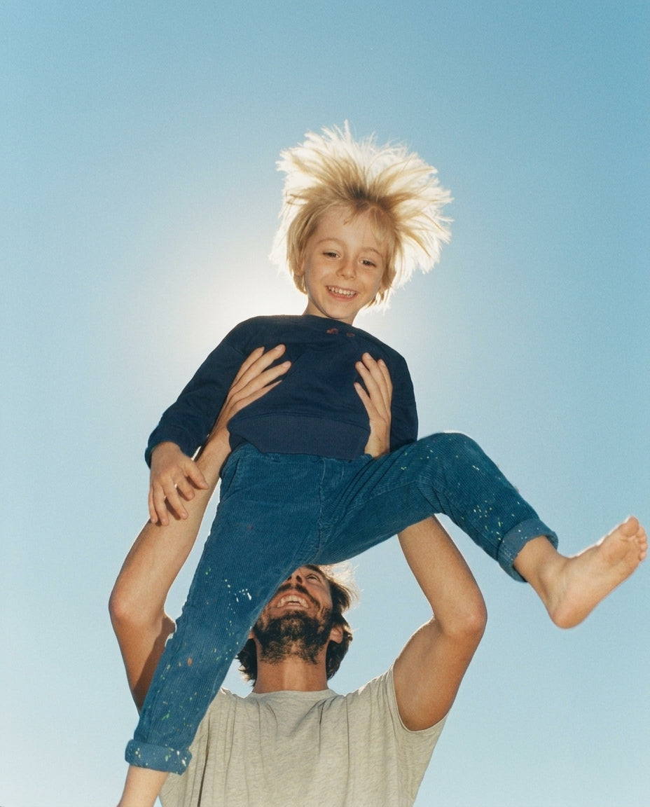 Parent lifting a child into the morning sun